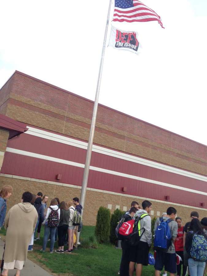 Students stand outside the flag pole.
