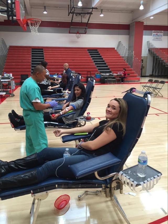 Students Gigi Ingifete ('16) and Sabrina Labrador ('16) smiling during the process with the knowledge that they're helping save lives.